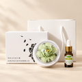 Green ceramic peony diffuser and oil gift set with clear cover, gift box and bag on a beige background