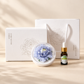 Periwinkle ceramic peony flower and oil gift set, large version — complete gift set on a beige background